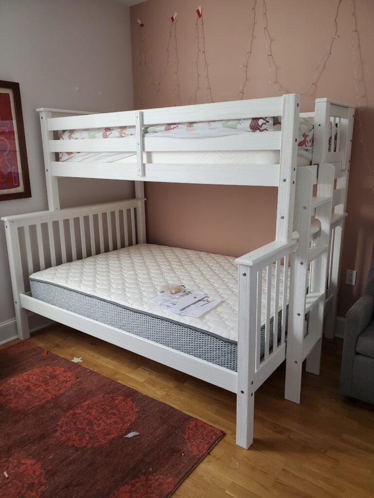 White bunk bed with a mattress assembled in a bedroom