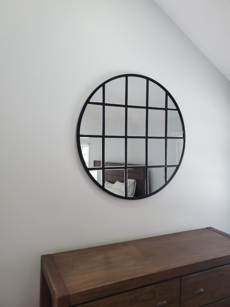 Round black-framed mirror hung above a dresser