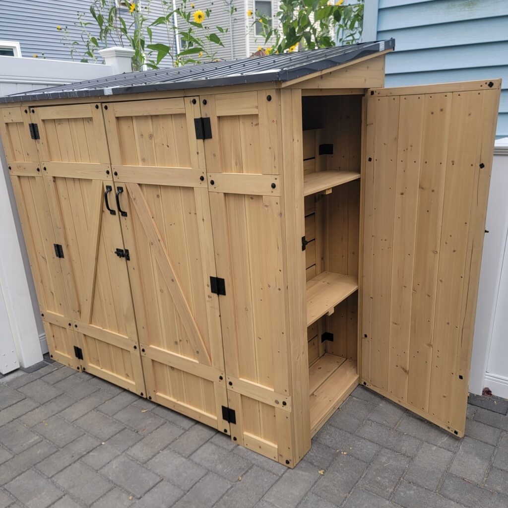 Wooden storage shed with a door open showing shelves inside