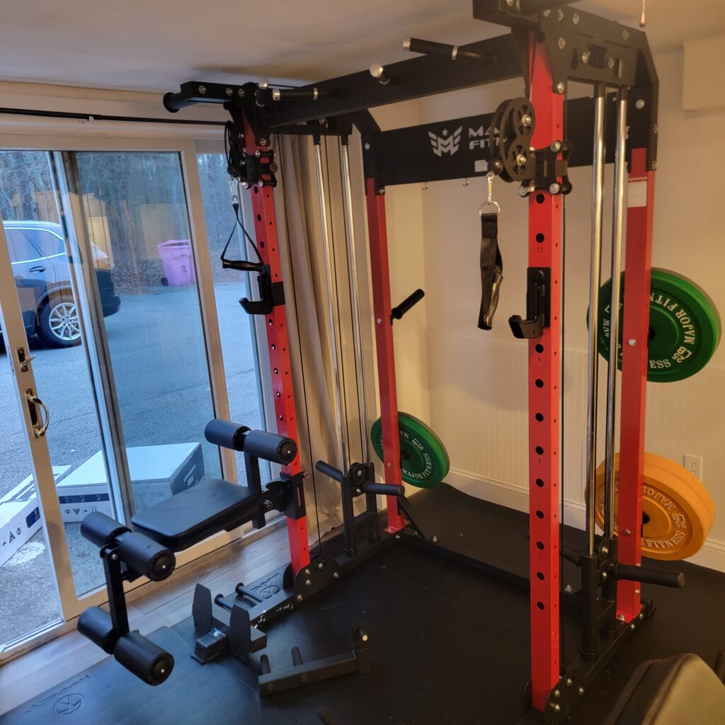 Red and black home gym rack with cable pulleys and weight plates