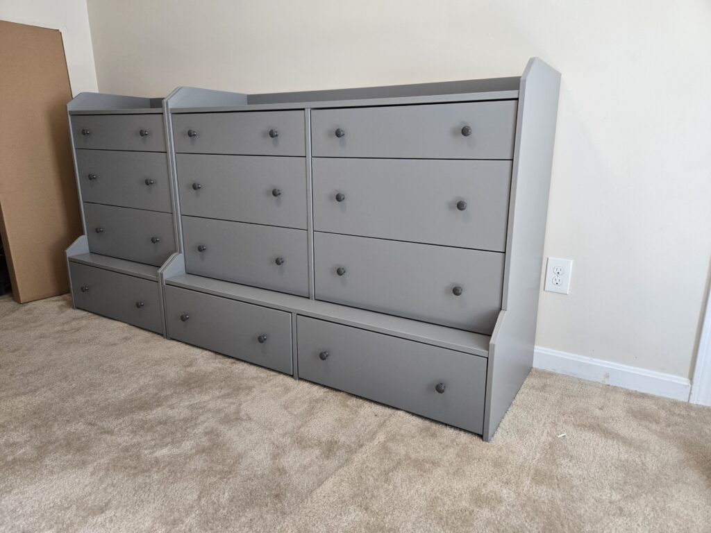 Two gray dressers assembled side by side in a bedroom