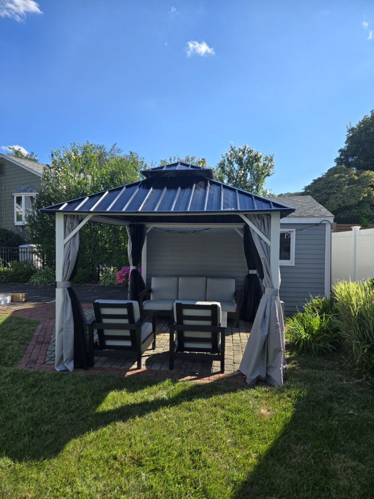 Hardtop gazebo with patio furniture in a backyard