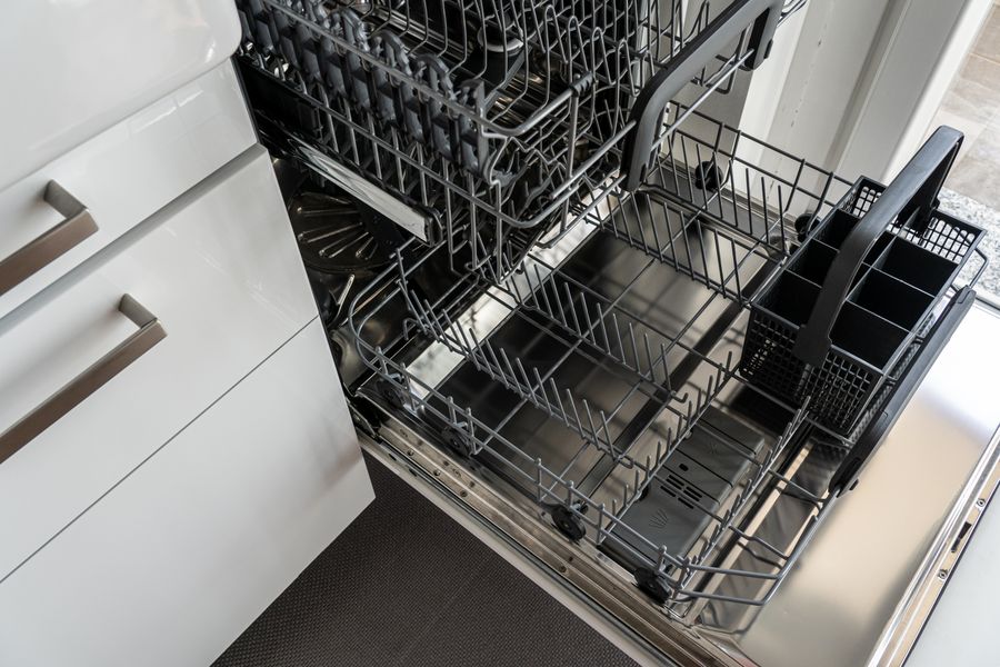 Open stainless-steel dishwasher in a modern white kitchen