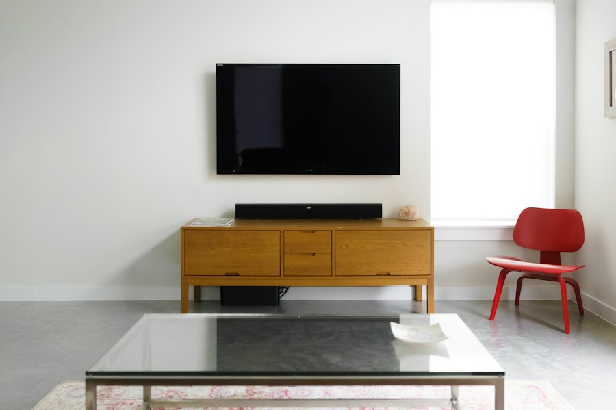 Flat-screen TV mounted on a white wall above a wooden media console